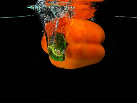 Orange pepper falling into waterの写真素材