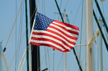 American flag on mast of a yacht standing in marinaの写真素材