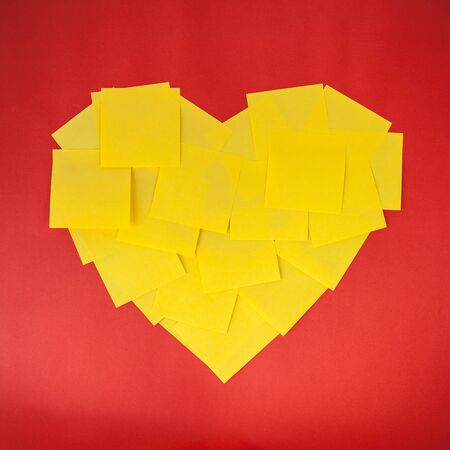 love shape by yellow notes on red paper background