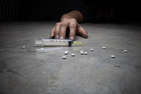 Close-up on the floor of the syringe with the drug. In the background, a young drug addictの写真素材