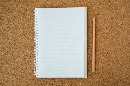 A cork board with a pencil and notebook.の写真素材
