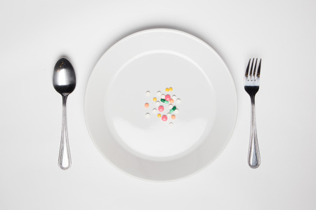 Medications and improper nutrition topic: human hand hold a plate with pill isolated on white background top viewの写真素材