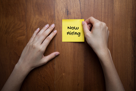 NOW HIRING ! message on the card shown by businesswomanの写真素材