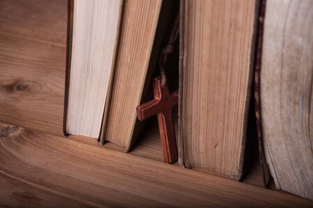 Closeup of wooden Christian cross necklace next to holy Bibleの写真素材