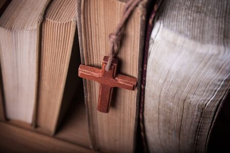 Closeup of wooden Christian cross necklace next to holy Bibleの写真素材