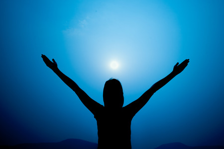 Silhouette of woman on a summit with upraised arms on the top mountain, Praise for GOD.の写真素材