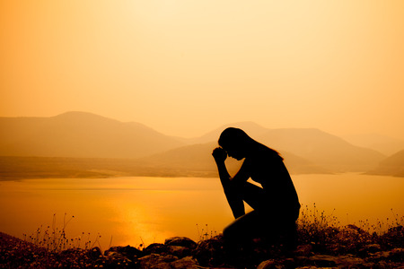 woman praying over amazing light sunset background. Religion conceptの写真素材