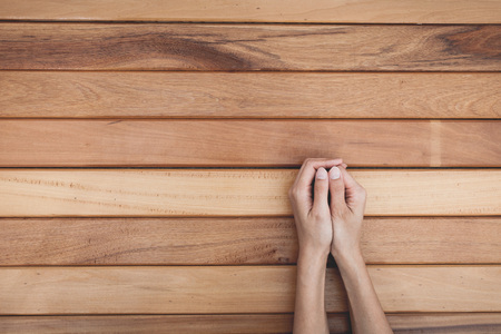 hands praying over wooden tableの写真素材