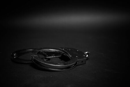 Short focus of police handcuffs on black background showing law conceptの写真素材