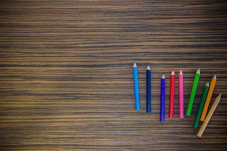 Colorful pencils on a wooden table, using for a background.