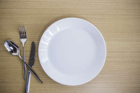Empty plate with spoon, knife and fork on a white background.の写真素材