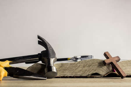 A hammer with Bible and a wooden cross on a wooden tableの写真素材