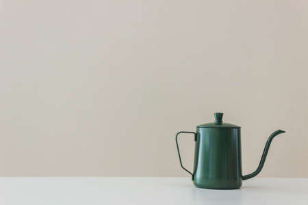 A dark kettle on table over the wall.の写真素材