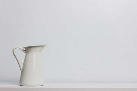 A white jug on table over a white background.の写真素材