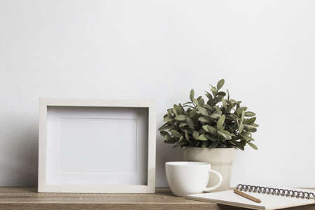 A mock up white note and a coffee mug with plant on table over a white background.の写真素材