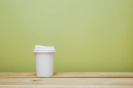 A coffee cup on table over the green wall.の写真素材
