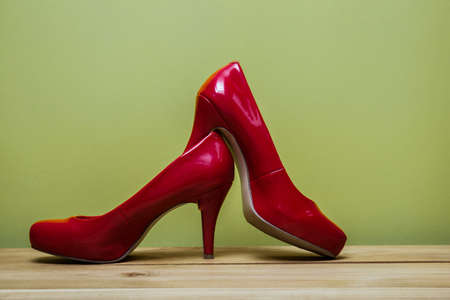 Red high heels on table over the green wall.の写真素材