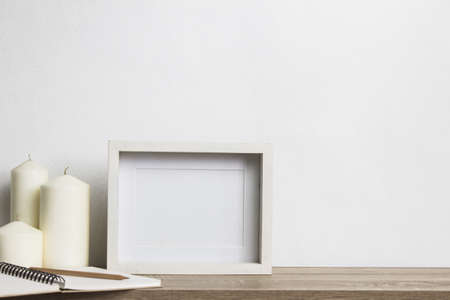 A mock up white photo frame with white candles on table.の写真素材