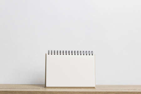 A mockup white note on a wooden table over the white wall.の写真素材