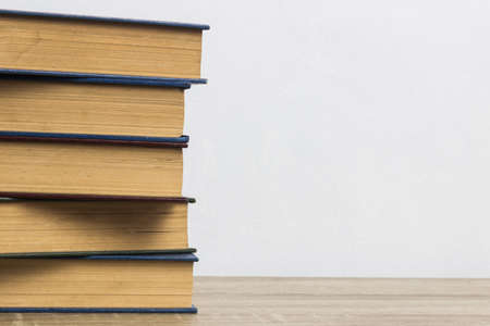 Books on a wooden table over the white wall.