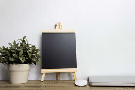 A plant and black note with computer device on table.