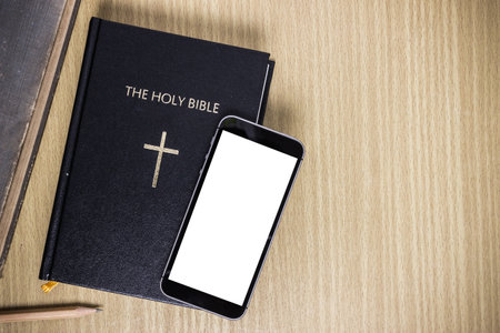 Bible with mock up mobile phone on a wooden table.の写真素材
