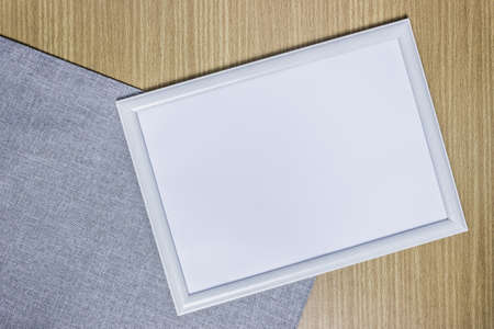 A white photo frame with wooden table.