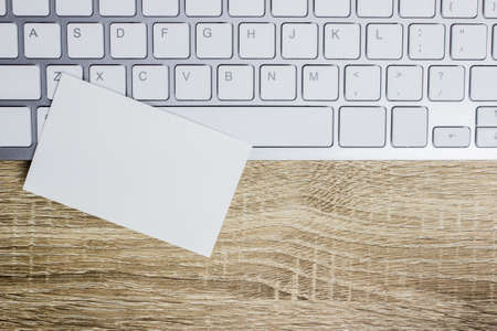 A white note with keyboard on a wooden table.の写真素材