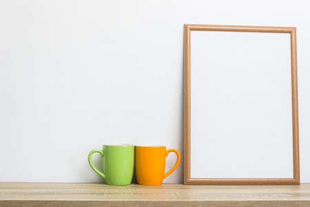 White frame with colorful coffee cups on wooden table.の写真素材