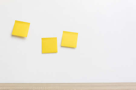 Three yellow sticker note on a white wall with copy space.の写真素材