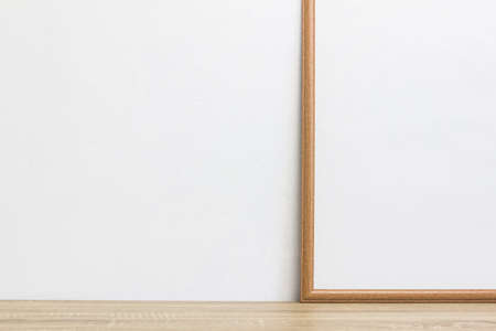 A white photo frame on a wooden table with copy space.