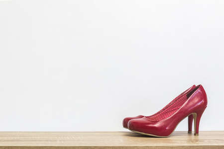 A high red shoes on a wooden table over the light wall.の写真素材