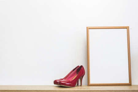 A high red shoes with a white frame on a table over the light wall.の写真素材
