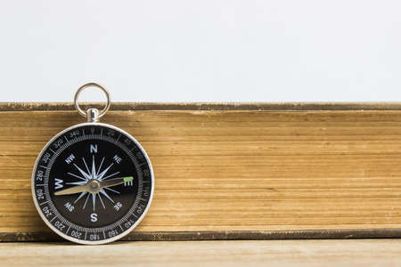 A Compass with book on table over the light background.の写真素材