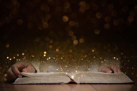 An opened Bible with gold bokeh for background.