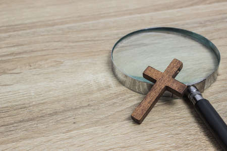 A magnifying glass with a cross on a wooden table.の写真素材