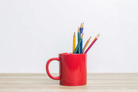 Colorful pencils in red cups on a wooden table.の写真素材