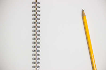 A white blank paper with yellow pencil on a wooden table.の写真素材