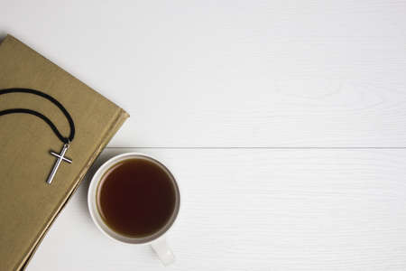 A cross on Bible with coffee on a white table.の写真素材