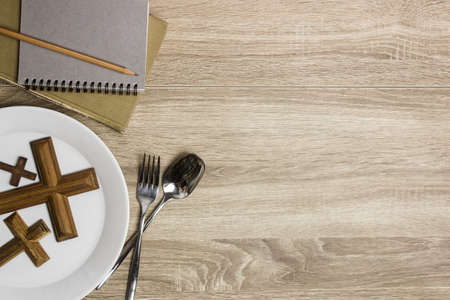 Wooden cross with Bible and notebook over the wooden table.の写真素材