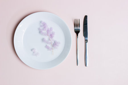 Sweet healthy concept with white plate, knife and fork on pink background.の写真素材