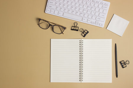 Working space with notebook, glasses, keyboard and pen on brown background.の写真素材