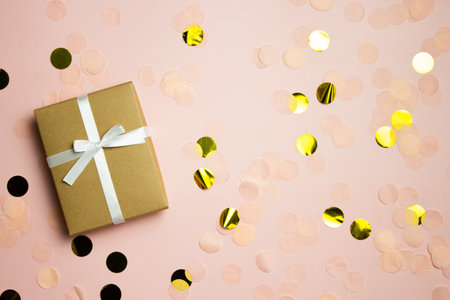 A brown gift box with golden paper over the pink background with copy space.の写真素材