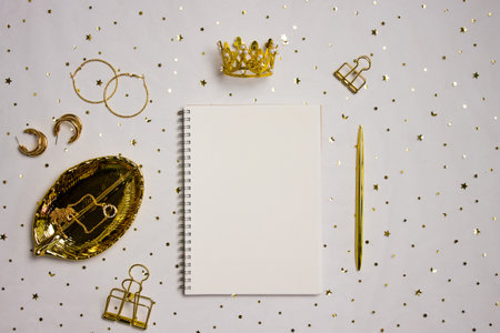 A notebook with golden items over the golden background.の写真素材