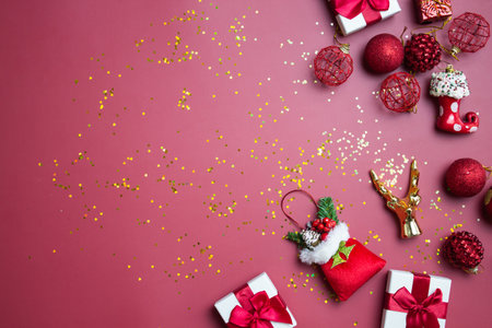 Christmas theme with red ornaments, gift box and golden golden glitter over the red background.の写真素材