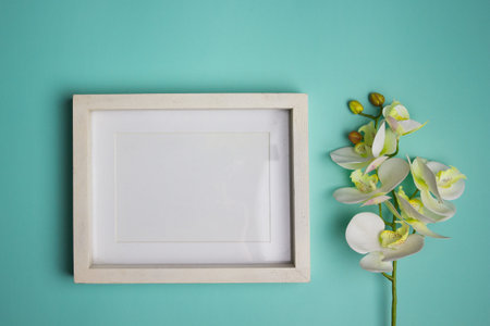 A wooden frame with an orchid on a mint background.の写真素材