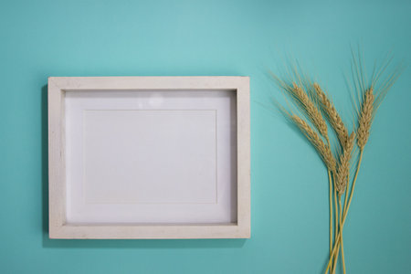 A white wooden frame with a wheat on a mint background.の写真素材