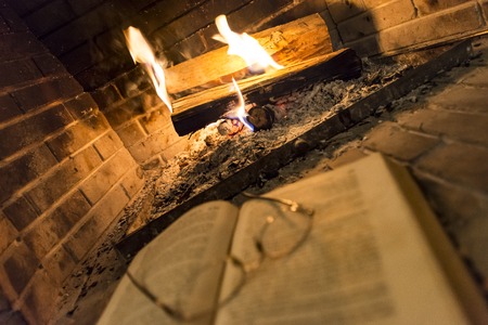 open book with glasses on it beside fireplaceの写真素材