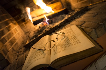 open book with glasses on it beside fireplace