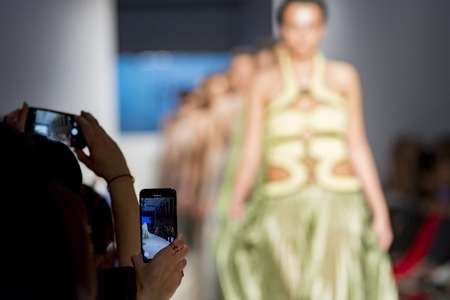 people from audience filming the fashion show with mobile phoneの写真素材